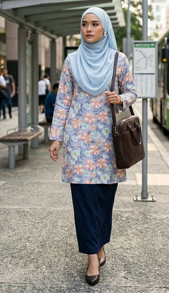 Woman wearing a floral dress and light blue hijab at a bus stop.