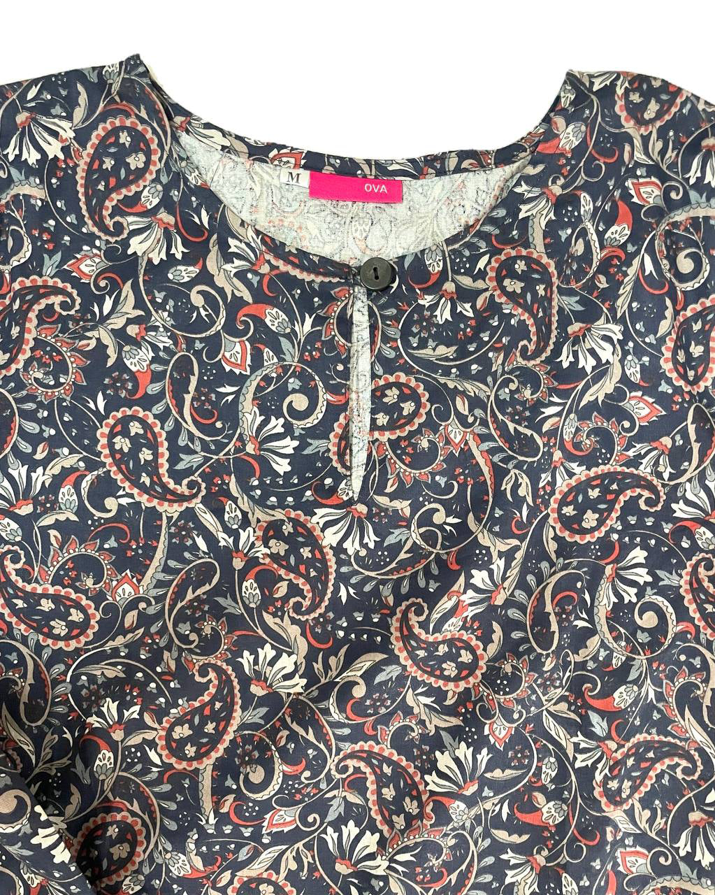 Close-up of Floral blouse with a button of round neckline with a visible brand label on a plain background
