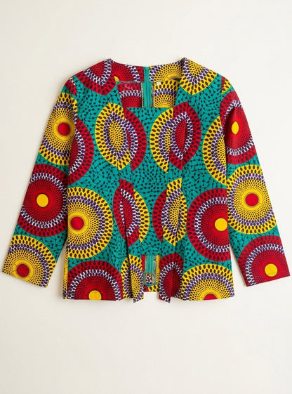 A women's long-sleeve blouse featuring a vibrant African wax print pattern with red, yellow, and teal circular motifs, displayed flat against a light off-white background.