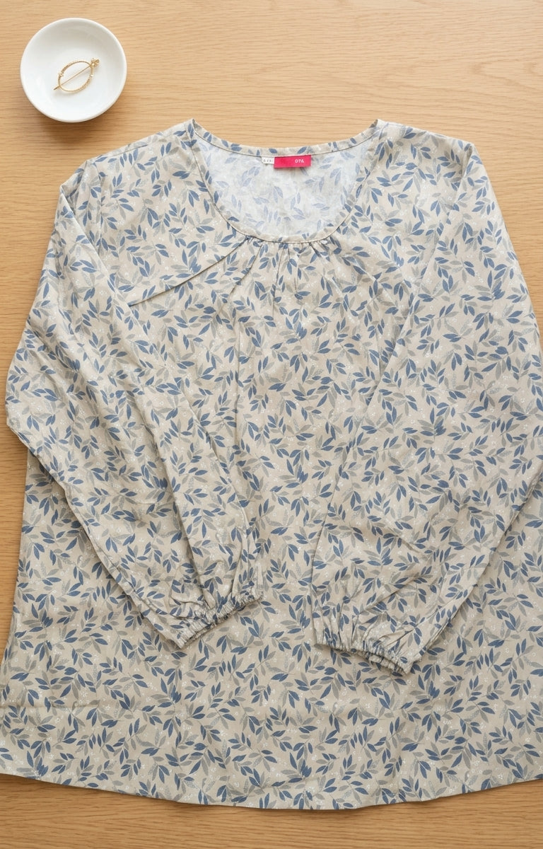 Floral-patterned shirt on a wooden surface with a small bowl in the corner.