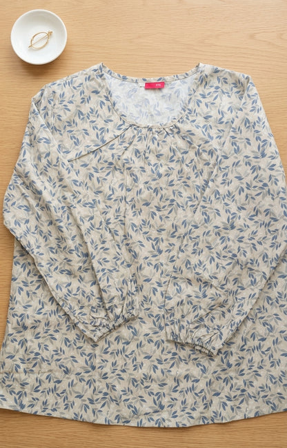 Floral-patterned shirt on a wooden surface with a small bowl in the corner.