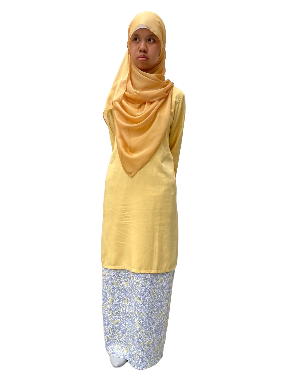 Woman wearing a yellow hijab and light yellow long bluse with a skirt floral pattern on a white background