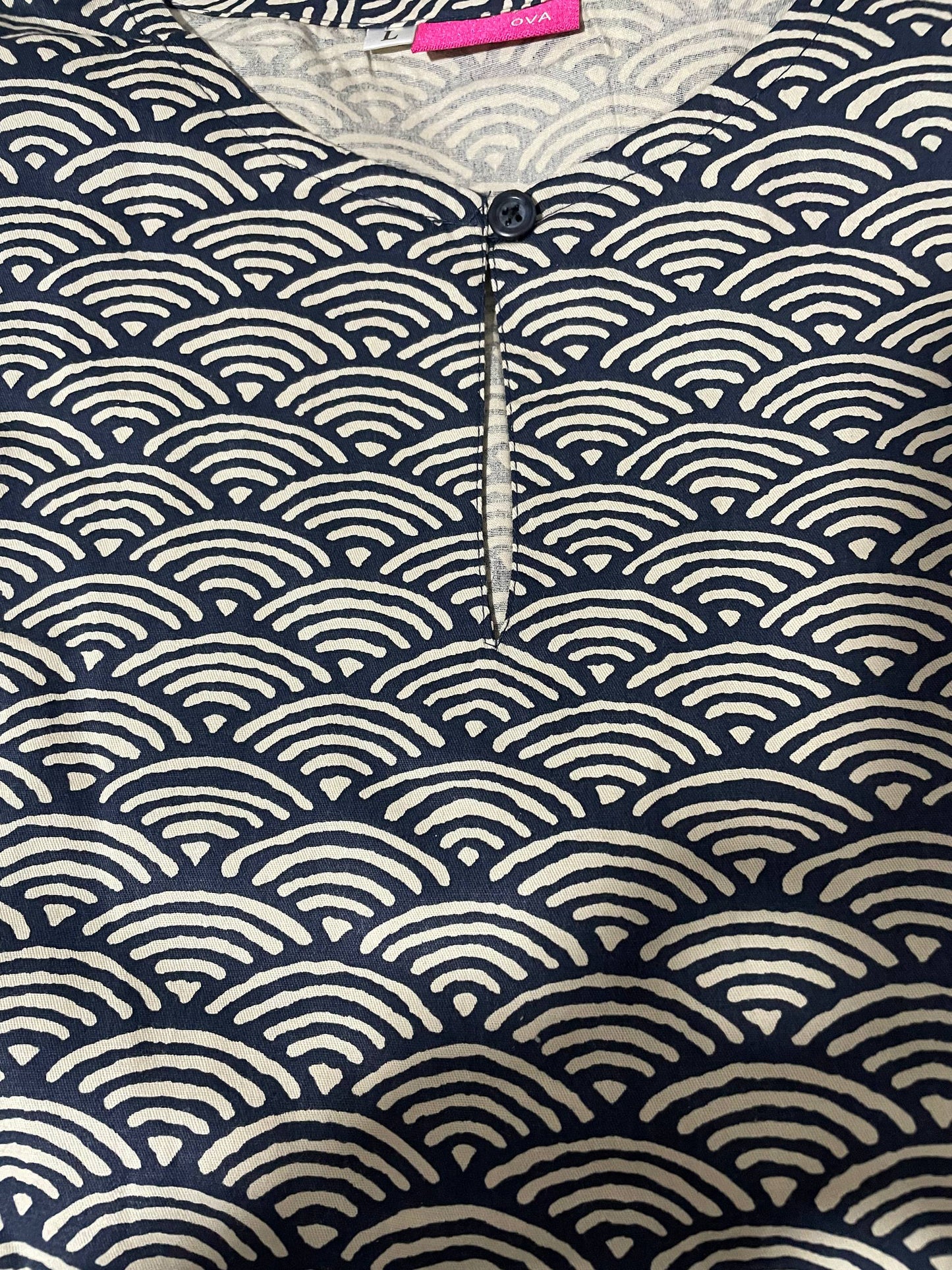 Close up of blouse with dark blue wave pattern and button detail