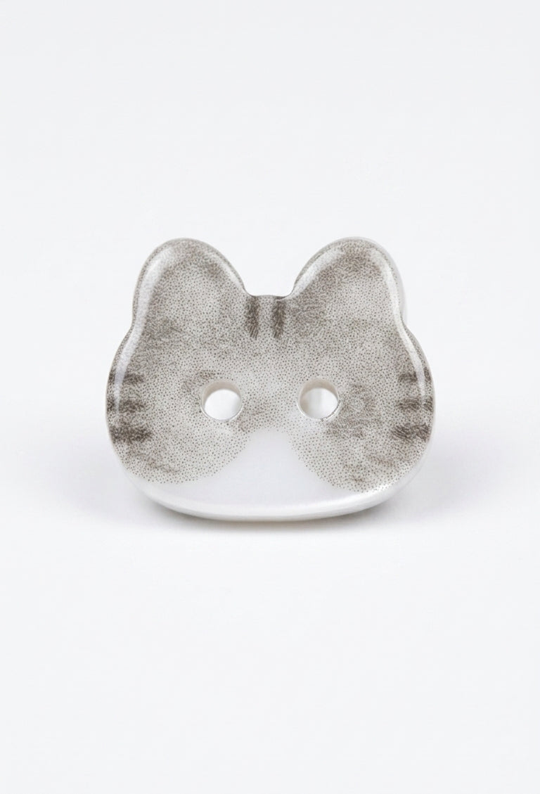 A single cat-shaped button with a textured silver-gray and white finish, featuring two holes for fastening, set against a plain white background.