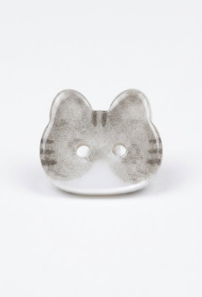 A single cat-shaped button with a textured silver-gray and white finish, featuring two holes for fastening, set against a plain white background.