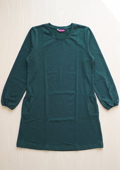 A dark green long-sleeve tunic tee with side pockets, laid flat on a light wood background.