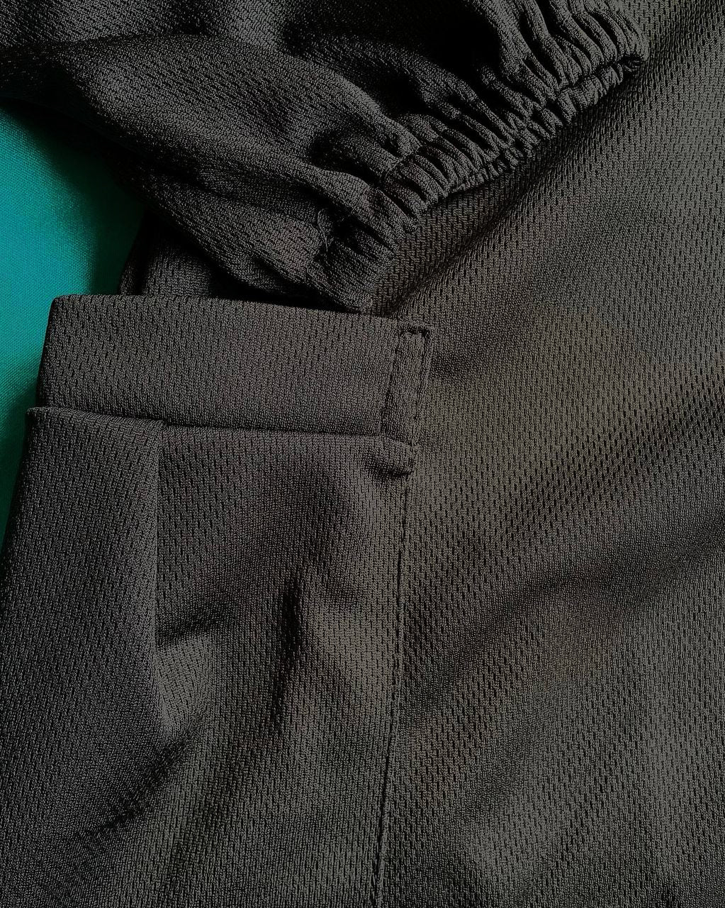 Close-up of dark gray dry fit t-shirt on a teal background