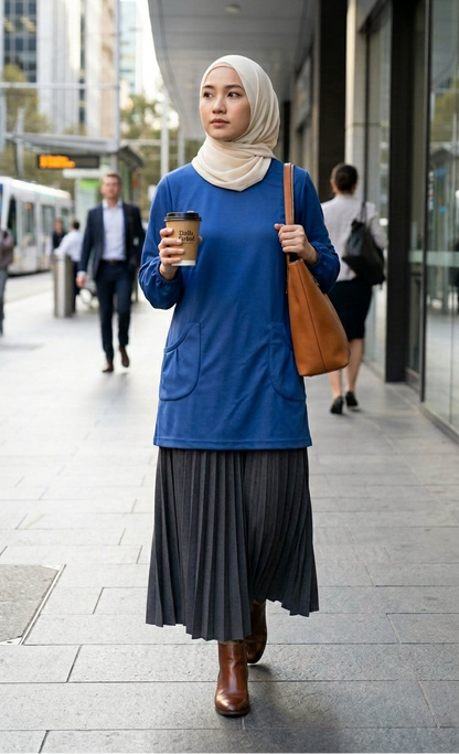 model with blue t shirt and skirt carrying a bag and coffee walking in the streets