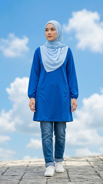 Person wearing a blue outfit with a hijab against a blue sky with clouds