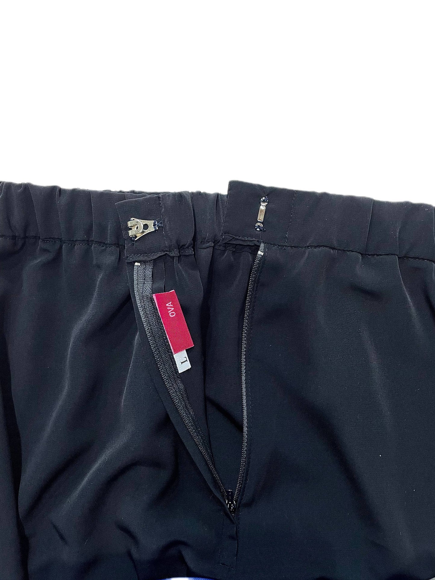 Close-up of black skirt showing the waistband, zipper, and a red interior brand tag reading 'OVA'.