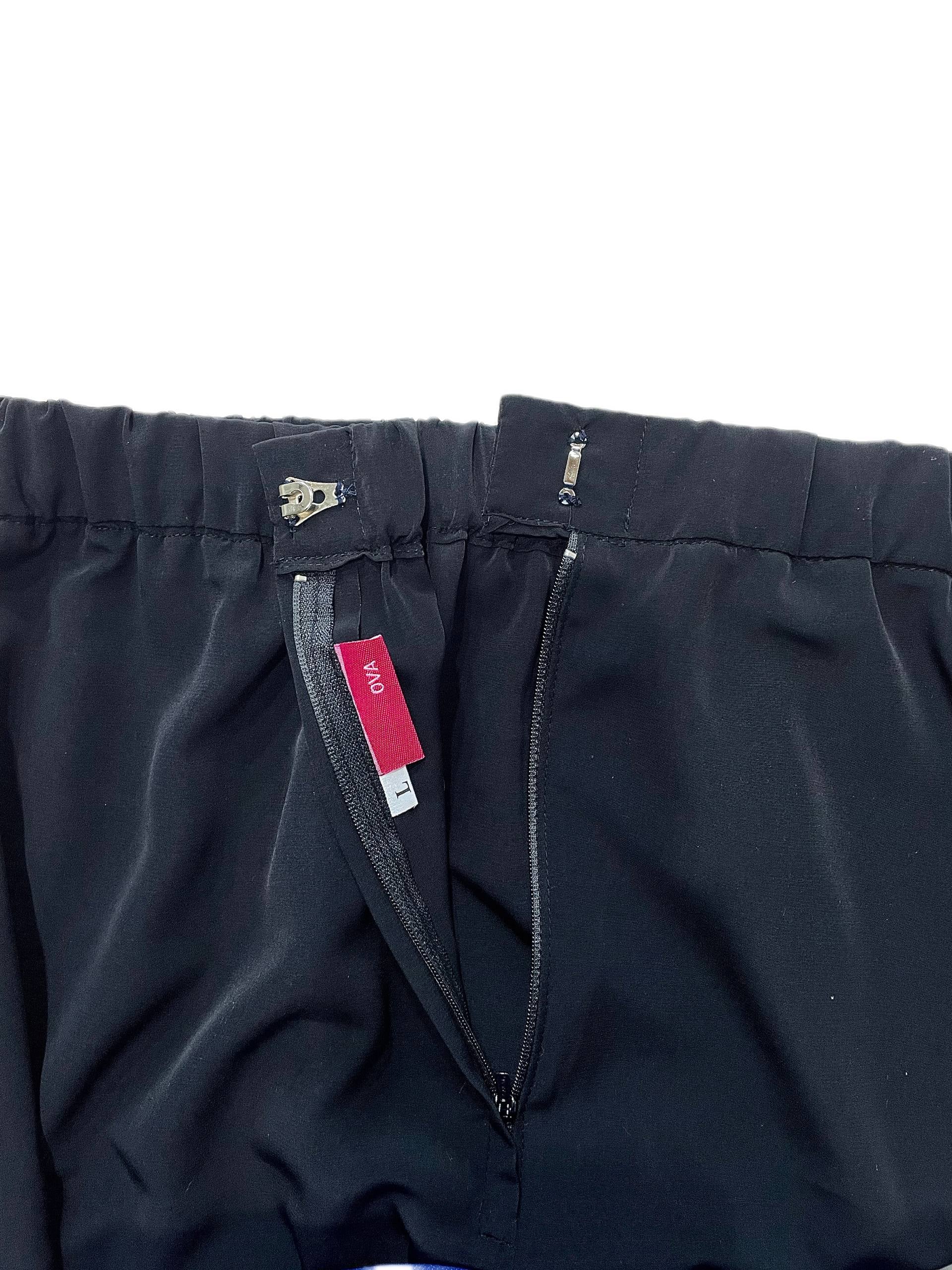 Close-up of black skirt showing the waistband, zipper, and a red interior brand tag reading 'OVA'.
