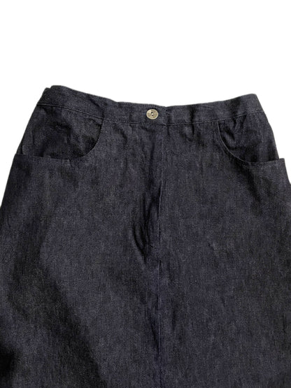 Close-up of the waistband and upper front of dark indigo blue denim skirt, showing a single metal button and side pocket seams against a plain white background.