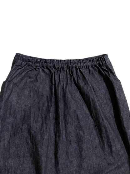 Close-up of a dark indigo blue denim skirt, showing an elastic waistband and gathered folds against a plain white background.