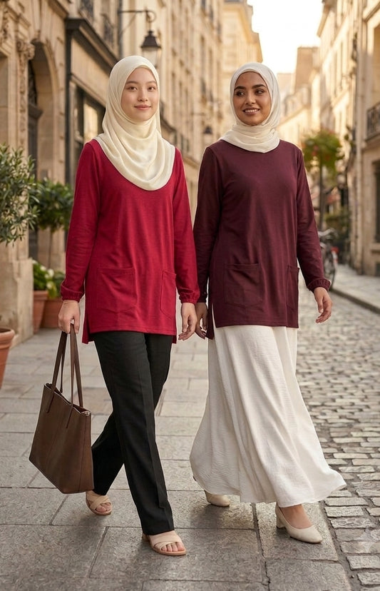 Two women walking down a street, wearing hijabs and long-sleeve tops.